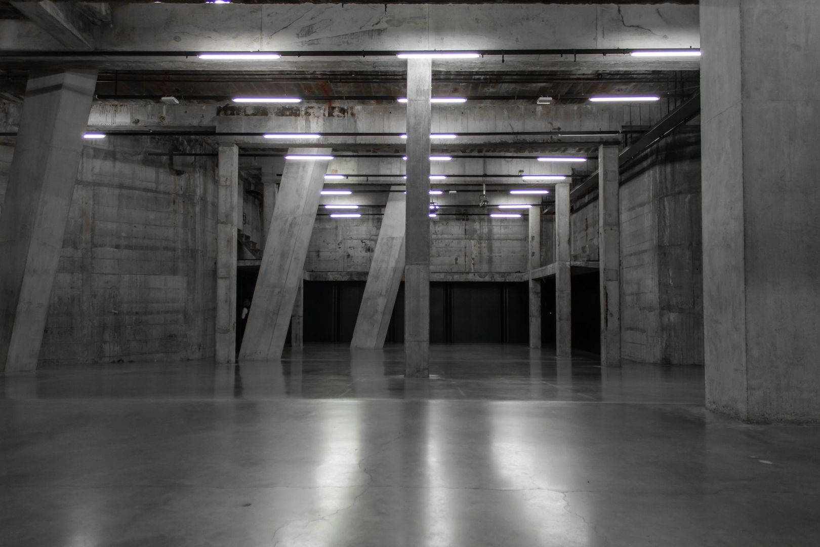 Empty concrete industrial hall with exposed beams and fluorescent lights